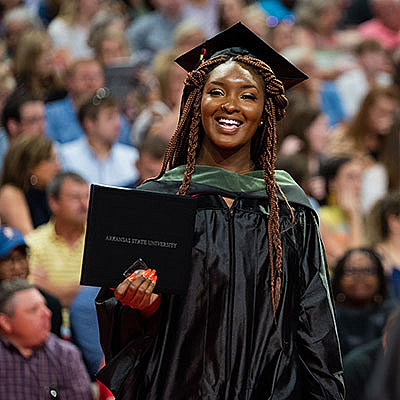 A student shows off her diploma at a 2019 commencement ceremony